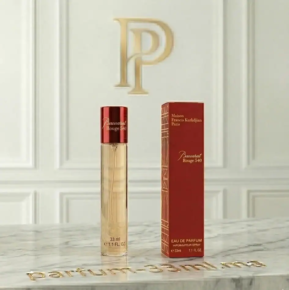 Flacon de parfum 33ml Baccarat Rouge 540 avec son bouchon rouge métallisé et sa boîte rouge iconique aux détails dorés sur un comptoir en marbre blanc.